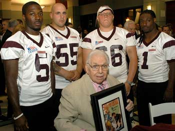 Jerry O’Brien (FCRH ’43), seated, received a framed cover of the program for the Sugar Bowl of 1942 from the captains of the Fordham football team during a banquet celebrating 150 years of Fordham football. The players are from left: Sam Orah, Michael Nardone, Michael Breznicky and Earl Hudnell Photo by Ken Levinson