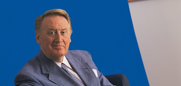 Fordham alumnus Vin Scully, the legendary sportscaster and Voice of the Dodgers, wearing a blue sport coat and sitting in front of a blue background.