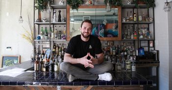 Fordham graduate Matt Trebek sits on the bar at Oso, the Mexican restaurant he opened in 2016 in the Harlem's Hamilton Heights neighborhood.