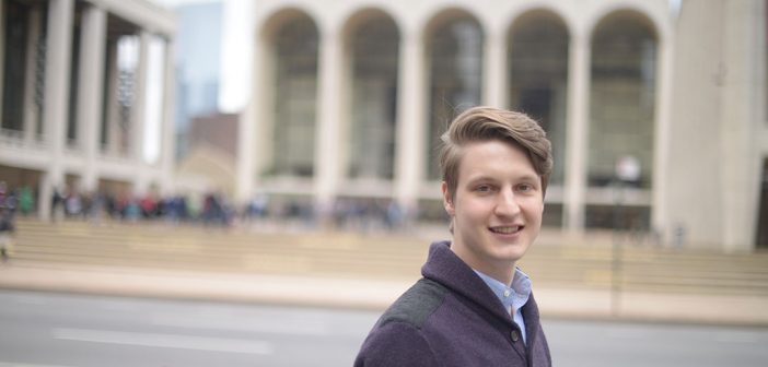 Alex McCauley standing in front of Lincoln Center, with hte Metropolitan Opera behind him.