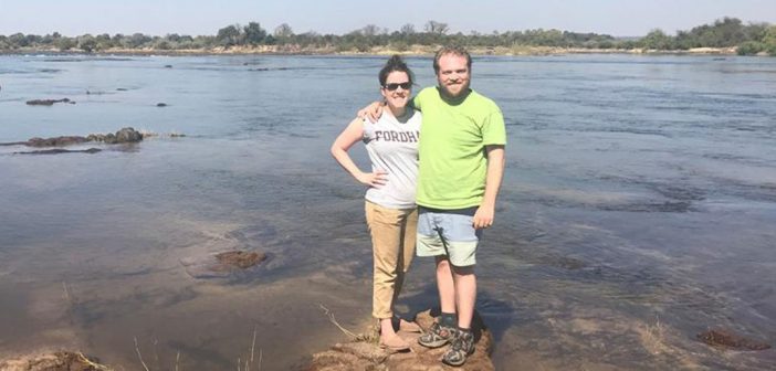 Fordham alumni Whitney Rog and her husband, Justin Lucas, stand on a rock in a river in Zambia, where they spent some time this summer assisting residents in establishing a small school for children in a rural village in Livingstone.