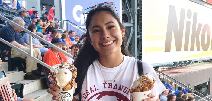 Female international student with black hair holding two ice cream cones at a Mets game
