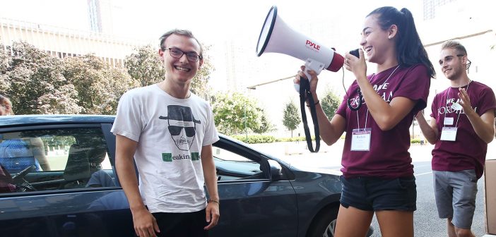 A first year student grins as he's cerenated by a student volunteer with a bullhorn at hte Lincoln Center campus