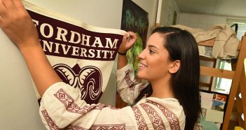 Olivia Jones, a first year student at Fordham College at Rose Hill, hangs a Fordham banner in her room at Alumni Court South