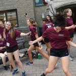 Student volunteers dance in front of the entrance of Martyr's Court on the Rose Hill campus.