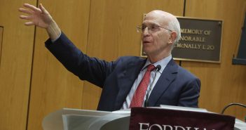 Economist Alan Blinder with outstretched arm at podium at Fordham
