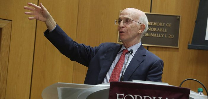 Economist Alan Blinder with outstretched arm at podium at Fordham