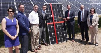 Executives stand in front of a solar panel