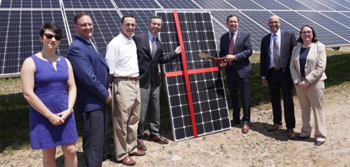 Executives stand in front of a solar panel