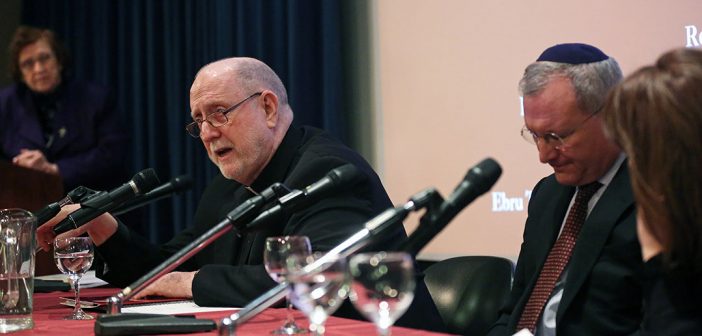 Father Ryan speaks into the mic beside two respondents at the 2018 fall McGinley lecture