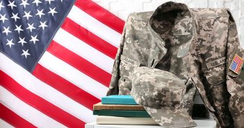 A camouflage military uniform draped over a chair with books