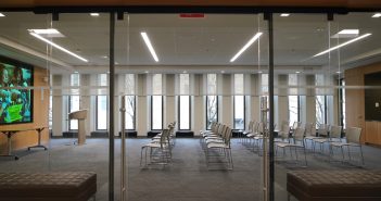 Panoramic view of the admissions office's new presentation area, featuring a wide-screen TV, four rows of chairs, and glass doors.