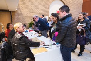 Lidia Bastianich signs copies of her book for a student standing in front of her, in the McNally Amphitheatre atrium