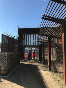A gate at the U.S. Mexican border topped with razor wire