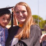 Blond woman holds a child wearing an academic cap