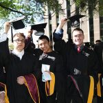 Five graduates raising their black caps