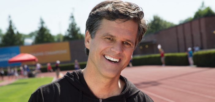 Timothy Shriver, Board Chair of the Special Olympics, in a black hoodie on an athletic track/field