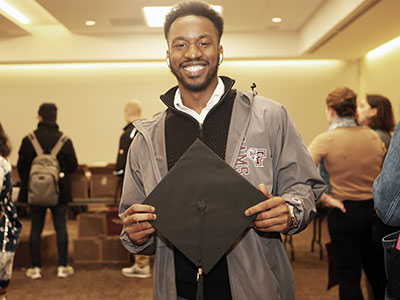 PCS graduate Tyler Brown holding a graduation cap