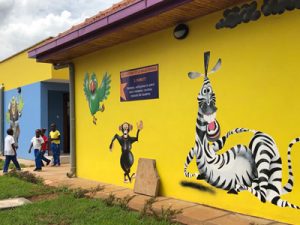 A bright yellow building wall with painted cartoon animals