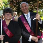 A man and woman wearing dressed in formal clothes sport red sashes
