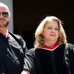 A man and woman wearing black academic robes