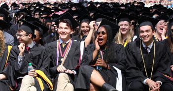 Graduates seated, wearing black academic robes