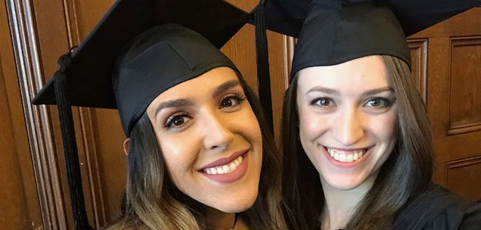 Close up of two women graduates smiling while wearing academic hats