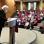 Rowan Williams speaks on stage at the McNally Amphitheatre as audience members look on.
