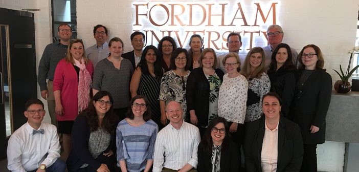 Members of the faculty who presented their research in London pose in front of a Fordham sign.