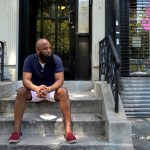 A man sits on a stoop in Harlem.