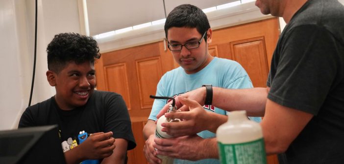 Two high school students work on scientific devices.