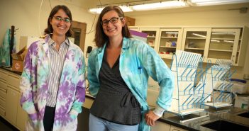 Two women wearing tie-dyed lab coats