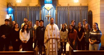 Father Elias Villis, a priest at Christ Our Savior Greek Orthodox Church, stands in the Keating Blue Chapel with students who attended a service there.