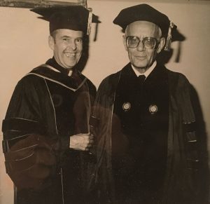 college graduate with priest 