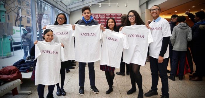 Students holding white Fordham t-shirts