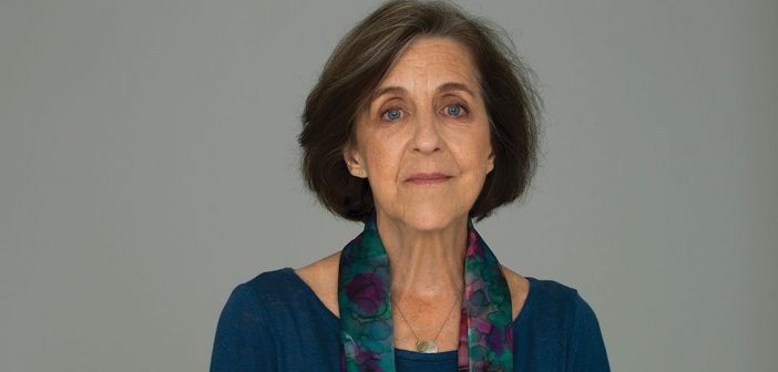 A portrait of Fordham graduate Dr. Rita Charon, the founder of narrative medicine, wearing a blue dress and scarf against a gray background