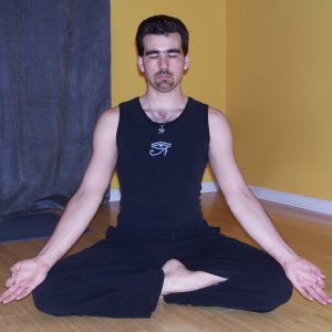 A man sitting cross-legged with his eyes closed and arms extended