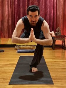 A man standing on a yoga mat with one leg on the floor