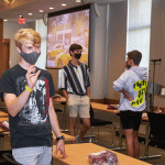 Masked students standing indoors and moving arms in orientation exercise