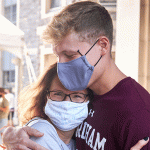 Young man hugging older woman, both with face masks