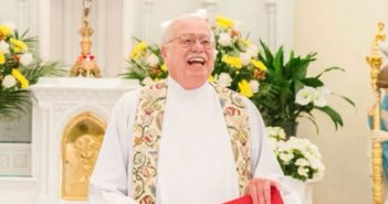 Father John Denniston standing at an altar