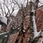 Statue with outstretched hand toward snowy bare trees