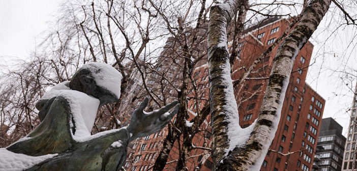 Statue with outstretched hand toward snowy bare trees