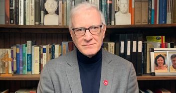 Tom Hughes, GSAS ’79, poses in front of a bookshelf.