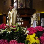 Priest on altar in University Church with flowers