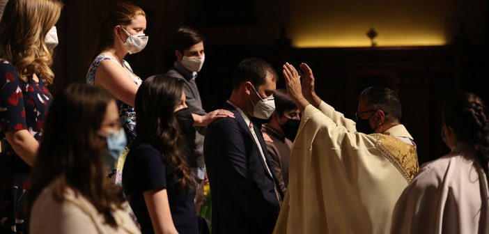 Priest praying over people getting confirmed in University Church
