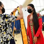 Student receiving yellow stole at AAPI graduation celebration in red dress