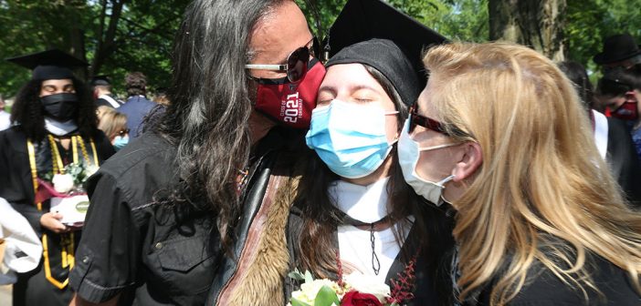 A grad getting kisses from two women on each cheek