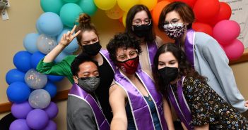 Students posing in front of rainbow balloons at LGBTQ Lavender Graduation with lavender stoles
