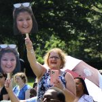 A family member holding a cardboard cutout of a graduate's face.